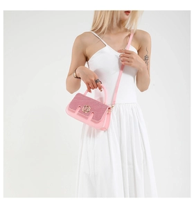 Close-up of pink contrast handbag with gold M logo on a white dress model