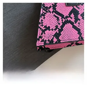 Close-up of pink and black snakeskin texture with detailed grain and black stitching