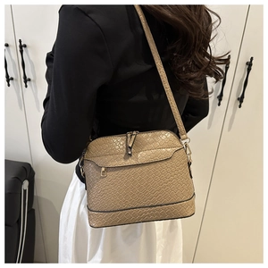 Détail d'un sac bandoulière beige tressé porté par un mannequin pour un look décontracté