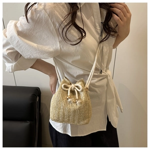 Detail of straw woven bucket bag featuring cotton drawstring and thin shoulder strap