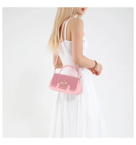 Close-up of pink fashion handbag with sparkling rhinestone flap and golden M logo detail
