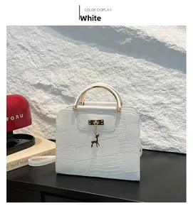 Close-up of white crocodile pattern leather bag with golden U-handle and deer pendant