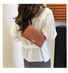 Close-up of caramel brown chevron quilted crossbody bag with gold metallic lock detail