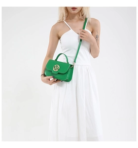 Detail of green mini crossbody bag with golden M buckle on smooth leather material