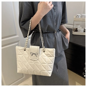 Détail macro du sac cabas matelassé blanc crème avec fermoir nœud en métal et bandoulière