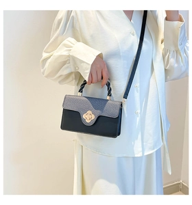 Detail of elegant two-tone handbag with a golden flower twist lock and braided handle
