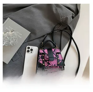 Detail of fuchsia snakeskin pattern handbag with black handle and gold studs