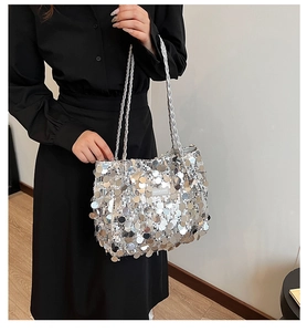 Close-up of sparkling silver sequin tote bag with woven straps and fashion brand label
