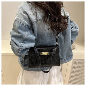 Side view of model wearing a black crocodile pattern crossbody bag with gold clasp