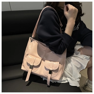 Close-up of pink patent leather shoulder bag with decorative pockets and silver buckles