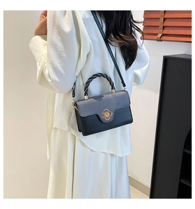 Detailed view of grey fabric and black leather texture with gold clover twist lock