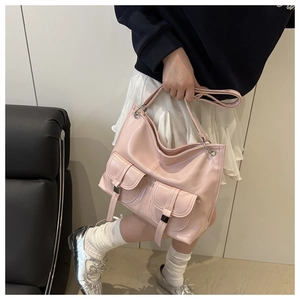 Detail of pink patent leather tote bag showing front pockets and metallic buckles