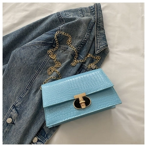 Detail of light blue crocodile embossed handbag with gold chain strap and T-bar lock