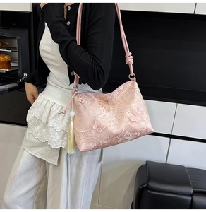 Detailed look at pink lace shoulder bag with butterfly embroidery and yellow tassel charm