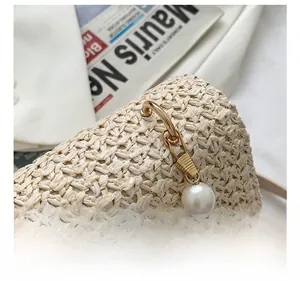 Detail of woven straw bag showing gold hardware hooks and elegant pearl charms