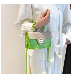Detail of canvas flap and green woven handle on a two-tone leather shoulder handbag