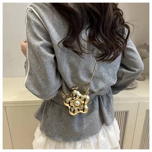 Detailansicht einer goldenen Blumen-Minitasche aus Metall mit Perle und feiner Kette