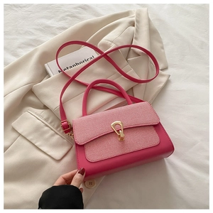 Detail of rose pink handbag with gold horseshoe buckle and woven texture on white bedding