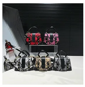 Five assorted snake pattern mini handbags in red, pink, white and grey on a tiered display