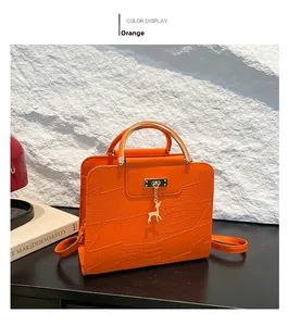 Detail of orange crocodile pattern leather bag with gold circular handle and deer pendant