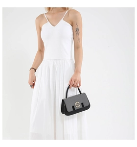 Detail of small square handbag with grey textured flap and golden letter M buckle