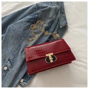 Detail view of burgundy croc-effect bag with gold hardware on denim jacket