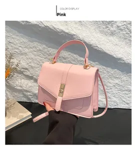 Bolso de cuero PU rosa con cierre giratorio dorado y correa sobre fondo de mármol liso