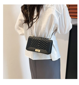 Close-up of black V-quilted faux leather shoulder bag with a gold metal twist lock buckle