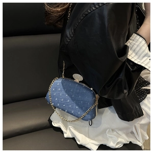 Detail of blue denim hard-shell clutch with sparkling diamond clasp and gold chain strap