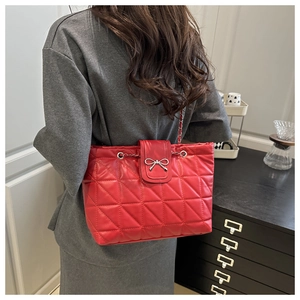 Detail of red quilted shoulder bag with silver bow buckle on model in office setting
