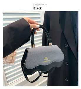 Close-up of color-block grey and black crossbody bag with wavy edge and golden logo
