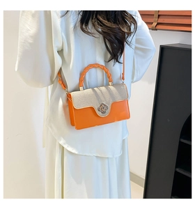 Detail of orange leather shoulder bag with straw woven flap and floral metal clasp