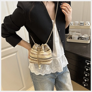 Détail du sac seau tressé avec chaîne dorée et breloques décoratives en perles
