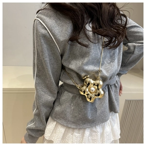 Detail der blumenförmigen goldenen Mini-Tasche aus Metall mit Perle und Kette