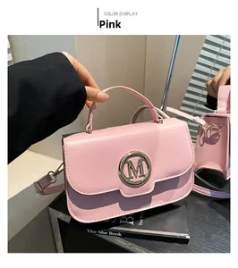 Detailed shot of pink PU leather handbag with gold M logo and slim shoulder strap