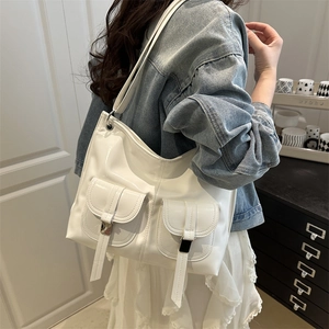 Chic white glossy tote bag with dual front pockets worn by a model in a minimalist room