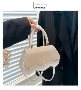 Close-up of cream white crossbody bag featuring woven texture and wave edge flap detail