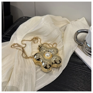 Detailansicht der goldenen metallischen Blumentasche mit Perle auf seidigem Stoff