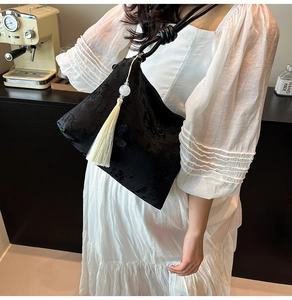 Détail du sac cabas en jacquard noir avec pompon élégant et breloque en perles