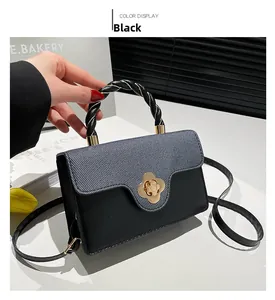 Detailed shot of black leather handbag with gold flower clasp and woven handle texture