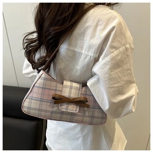 Close-up of pink and blue checkered underarm bag featuring a brown leather bow detail