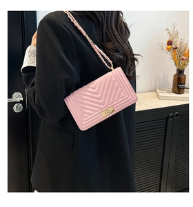 Detail of pink quilted shoulder bag with V-shaped stitching and golden metal lock