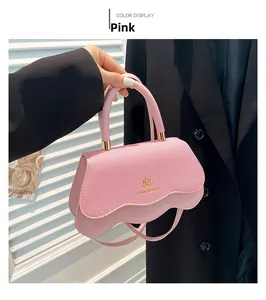 Detail of pink small square bag featuring scalloped flap and gold metallic hardware