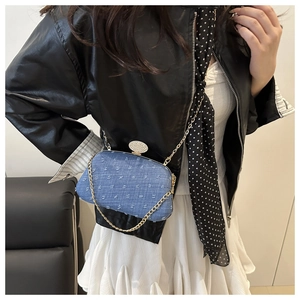Detail of denim clutch bag with star patterns, rhinestone buckle, and gold chain strap