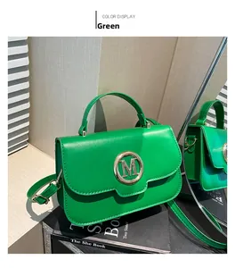 Detail view of a green leather handbag featuring a golden M buckle and adjustable strap