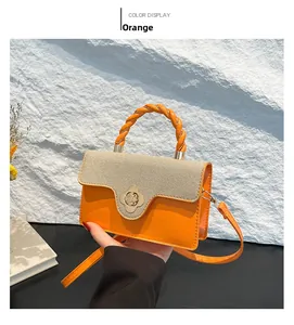 Detail of orange and beige handbag with twisted handle and golden flower clasp