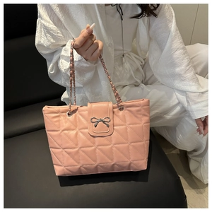 Detail of pink quilted tote bag with a silver bow clasp and elegant chain shoulder strap