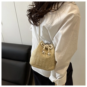 Detail of hand-woven straw bucket bag with drawstring closure and rope shoulder strap