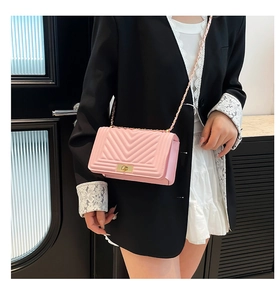 Pink chevron quilted crossbody bag with gold chain strap worn with a black blazer
