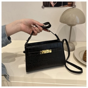 Close-up of black crocodile embossed texture and golden metal buckle on handbag